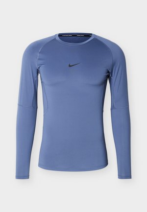 Garām piedurknēm piemērota zilā Nike sporta krekls ar apaļu kaklu un melnu swoosh logo krūtīs centrā.
