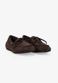 Zapatos mocasines de ante marrón con detalle de cordones, puntera redondeada y suela baja de goma negra. Presenta ojales plateados para los cordones.