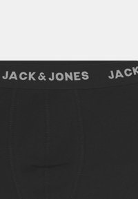 Svarta boxershorts med ett grått elastiskt midjeband som visar "JACK & JONES" i fet stil och en tät, åtsittande design. Slät tygtextur.