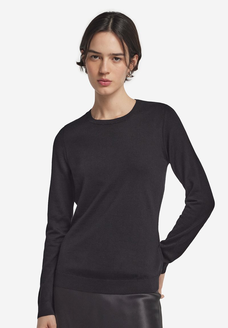 Sort langærmet sweater i glat strikket stof med rund halsudskæring, tætsiddende silhuet og ribstrikkede manchetter og kant. Ingen bemærkelsesværdige mønstre eller accenter.