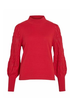 Pull rouge à col montant, avec un corps en tricot uni et des manches ballons en dentelle texturée à motifs. Bas des manches et ourlet en côtes.