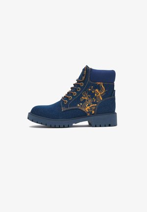Blå denim snørestøvle til anklen med brun dragedesign på siden og tyk gummisål.
