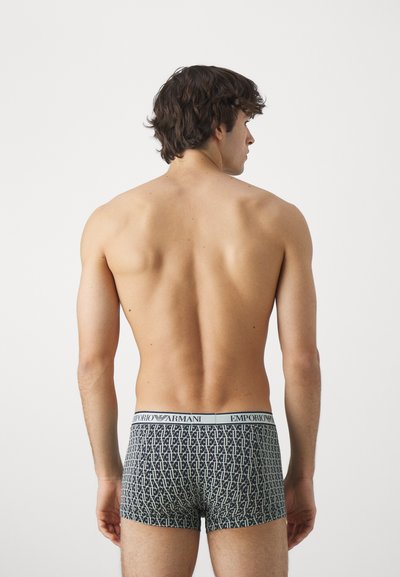 Čierne a béžové boxerky s vzorom, s elastickým pásom a logom "Emporio Armani", zobrazené zozadu na modeli.