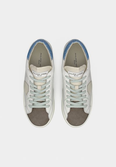 Λευκά αθλητικά παπούτσια με γκρι και μπλε λεπτομέρειες, με ανάγλυφο μπλε τακούνι, κορδόνια και συνδυασμό δέρματος και σουέτ υλικών.