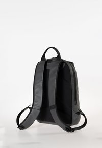 Zaino nero con spallacci imbottiti, texture liscia e manico superiore. Presenta un'apertura con zip e un design elegante e strutturato.