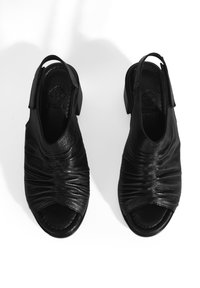 Zwarte leren slingback schoenen met een geplooide textuur, open teen en een lage blokhak. Eenvoudig ontwerp met een gladde afwerking en geen zichtbare hardware.