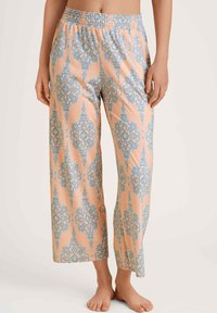 Lichte, perzikkleurige pyjamabroek met een blauw damastpatroon, wijde pijpen en een smockband voor comfort.