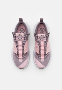 Zapatillas deportivas en colores rosa y gris con una parte superior de malla texturizada, suela flexible y un patrón en contraste. Cuenta con un cuello acolchado y un diseño de cordones.