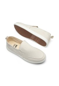 Beige Slip-On-Schuhe aus Baumwollcanvas mit strukturierten Oberflächen, elastischen Seiteneinsätzen, weißen Gummisohlen und einem Fersenriemen zum einfachen Anziehen.