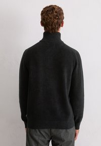 Pull en maille côtelée de couleur gris foncé, en matière douce. Il présente des poignets et un ourlet côtelés, avec une coupe ajustée et un design minimaliste.