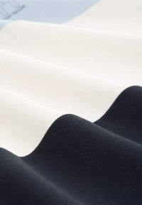 Tkanina tekstylna z trzema poziomymi falami w kolorach białym, kremowym i ciemnym granatowym. Tekstura wydaje się gładka i lekko prążkowana.