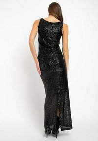 Schwarzes, mit Pailletten besetztes Kleid mit einer taillierten Form, ärmellosem Design und einem Oberschenkel-hohen Schlitz. Der Stoff hat eine glänzende, reflektierende Textur.