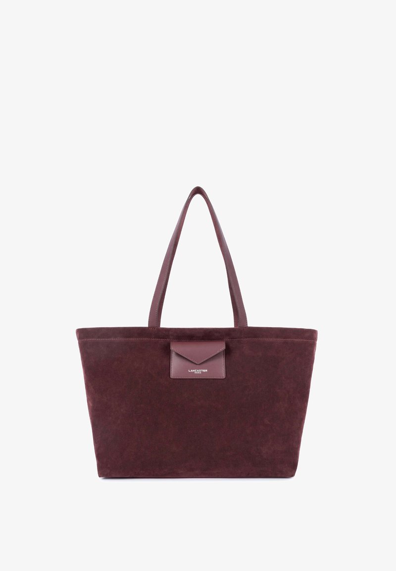Sac cabas en daim bordeaux foncé avec deux poignées et une petite poche avant portant l’étiquette Lancaster Paris.