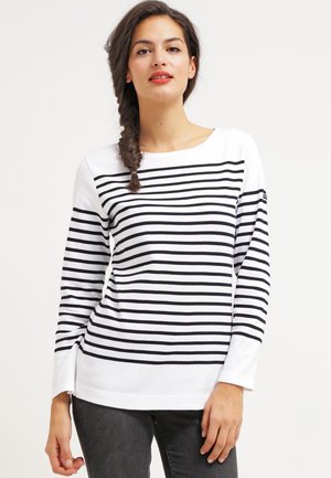 T-shirt à manches longues rayé en blanc et noir, avec des rayures horizontales, un col rond et une coupe décontractée. Le tissu semble doux et lisse.
