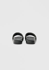 Black open-toe slide sandals with wide straps and contoured footbeds, viewed from the back on a plain gray background.