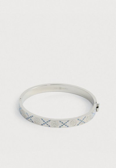 Ασημένια βραχιόλι με εγχάρακτους κυκλικούς λογότυπους και μπλε στρας σε μοτίβο Χ, διαθέτοντας ένα μικρό στρογγυλό κούμπωμα.