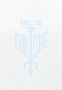 Λογότυπο Versace Jeans Couture σε ανοιχτό μπλε χρώμα σε λευκό φόντο, με στυλιζαρισμένο βέλος και σχέδιο φτερού ενσωματωμένα στο κείμενο.