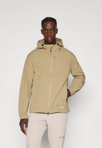 Light beige hooded jacket with a front zipper, elastic cuffs, and a chest pocket. Features a matte texture and minimal branding.
