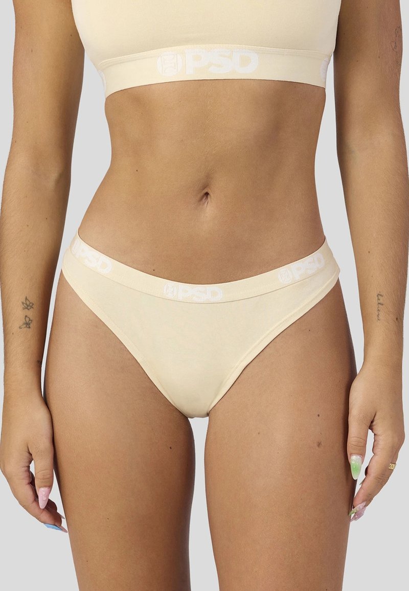Culotte beige en tissu doux avec une large ceinture blanche portant le logo "PSD". Le design est minimaliste et près du corps.