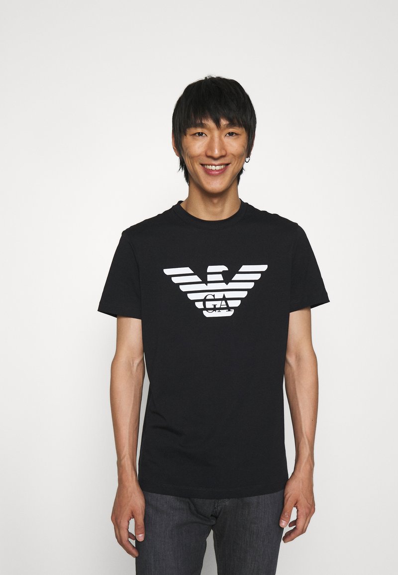 Black cotton t-shirt featuring a white graphic logo with winged stripes across the chest, round neckline, and short sleeves.