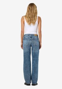 Ανοιχτό μπλε τζιν παντελόνι με άνετη γραμμή, με χαμηλή μέση, πίσω τσέπες και καφέ δερμάτινη ετικέτα στη ζώνη.