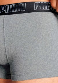 Shorts in cotone grigi con elastico nero che presenta il logo "PUMA" in caratteri azzurri. Tessuto morbido, design aderente.