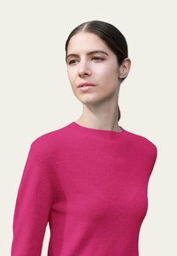 Pull en tricot fuchsia avec encolure ronde et motif texturé subtil sur le devant. Manches longues et tissu doux et lisse.