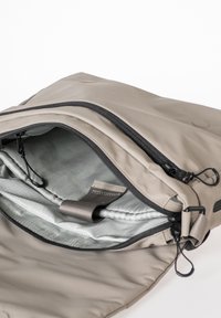 Zaino in nylon grigio con apertura con cerniera, tasca interna in rete e fodera liscia. Presenta hardware della cerniera nero e chiusura con cordino regolabile.