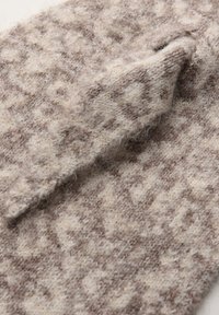 Tessuto in lana con una base beige chiaro e un motivo geometrico marrone. La superficie ha una consistenza morbida e pelosa con un'area piegata.