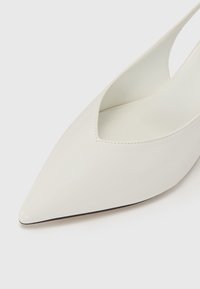 White leather high-heeled pump with a pointed toe and cut-out sides. Smooth texture and subtle stitching detail along the edges.