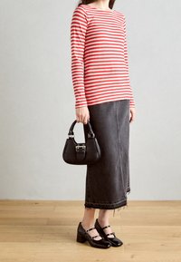 Rød og hvidstribet bluse med lange ærmer, sort denimskørt med fransede kanter, sort håndtaske med metaldetaljer, og sorte Mary Jane sko.