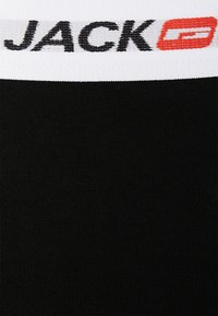 Schwarzer elastischer Bund mit der Aufschrift "JACK" in schwarzer und roter Schrift. Das Material des Körpers besteht aus einem glatten, gerippten Stoff.