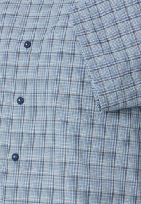 Blauw geblokt overhemd met knopen en een zak op de borst, met een rasterpatroon in verschillende tinten blauw, wit en enkele oranje accenten.