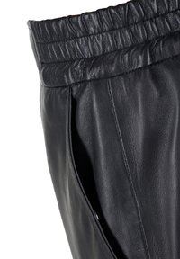 Schwarze Lederhose mit elastischem Bund und seitlichen Taschen, ausgestattet mit glatter Textur und stromlinienförmigem Design.