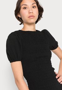 Vestido preto com mangas curtas bufantes, apresentando um design texturizado com franzido e um decote redondo, silhueta ajustada e material suave.