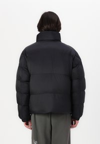 Svart boblejakke med høy krage, quiltet design og elastiske mansjetter. Stoffet virker glatt og lett, noe som gjør det passende for kaldt vær.