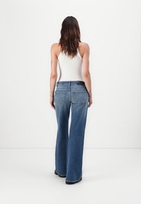 Blue high-waisted flared jeans with a classic five-pocket design, featuring a dark waistband and subtle fading on the legs.
