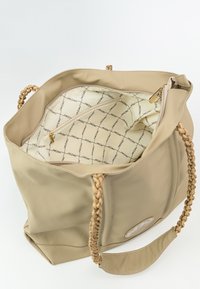 Borsa tote beige con manici intrecciati, materiale testurizzato e un interno caratterizzato da un tessuto stampato e una tasca con zip.
