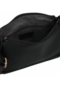 Interior de un bolso de mano de cuero negro que muestra una textura suave, un bolsillo con cremallera y un compartimento principal con un forro más oscuro. Se aprecian acentos de hardware dorado.