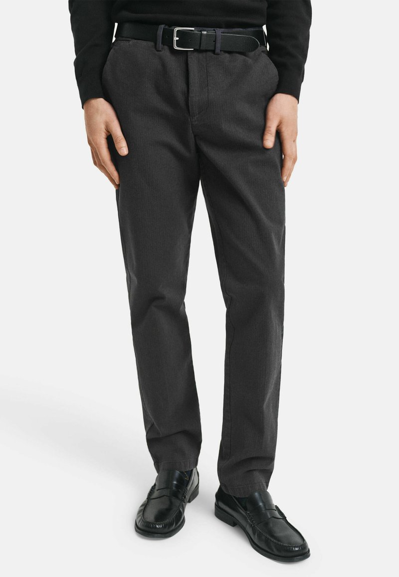Donkergrijze broek met een gestructureerde afwerking, rechte pasvorm en zijzakken, gecombineerd met een zwarte riem en zwarte lakschoenen.