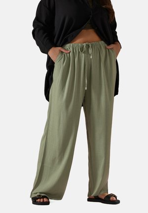 Light green, wide-leg pants with an elastic waist and drawstring. Smooth texture, made from breathable fabric, paired with black sandals.