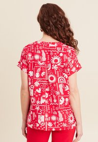 Top corto rosso a maniche corte con un motivo bianco che presenta forme come sole, piante e arcobaleni. Tessuto morbido, vestibilità comoda e dettaglio a pieghe sul retro.