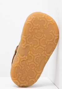 Ruskea kumipohja, jossa on leikkisä tekstuurimalli hymyilevistä kasvoista ja kiipeilijäfiguureista, ja sivussa on painettu koko "18".