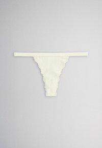 White lace thong underwear with a thin waistband laid flat on a light gray background.