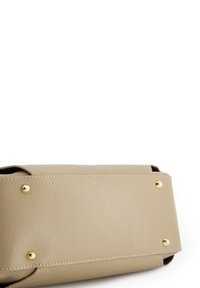 Sac à main en cuir beige avec une finition texturée, mettant en valeur des accents en métal doré et des clous métalliques protecteurs au fond pour la stabilité.