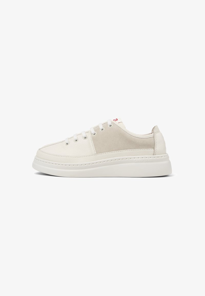 White sneaker with a smooth texture, featuring a light gray side panel, laces, and a thick sole. Clean and minimalist design.