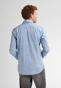 Camicia da uomo a maniche lunghe in azzurro chiaro con un motivo geometrico, caratterizzata da una texture morbida, colletto button-down e orlo curvo.
