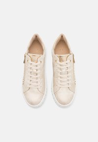 Sneakers beige realizzati in materiale liscio, con allacciatura frontale, dettaglio con zip dorata e suola in gomma bianca. Accenti perforati sui lati.