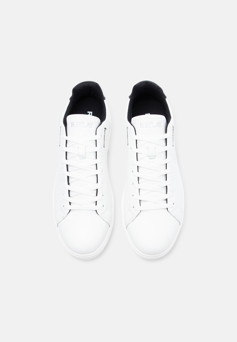 Zapatillas de deporte de cuero blanco con detalles en negro, puntera redonda, cordones planos y cuello acolchado. Presenta un logo en la lengüeta y una textura suave.