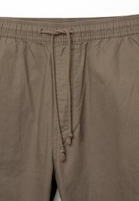 Bruine shorts met elastische tailleband en trekkoord, twee zijzakken en een gladde, lichtgewicht stofstructuur.